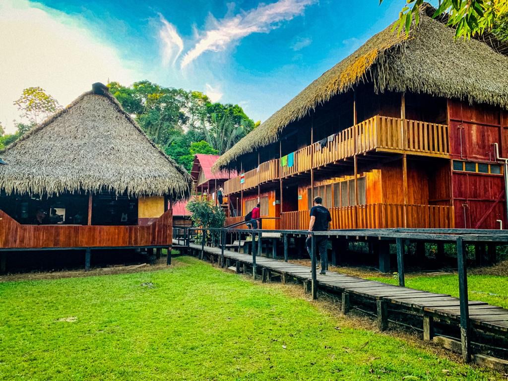 The wooden cabins of Cuyabeno Dolphin Lodge under a bright Amazon sky