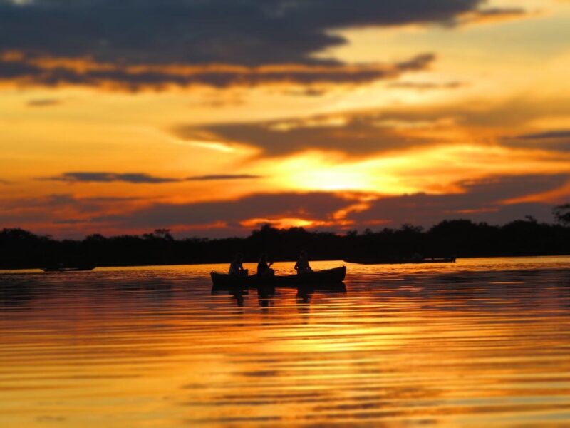Canoe crossing the Laguna Grande under a golden sunset in Cuyabeno